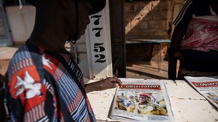 Un homme lit un journal sur lequel figure en première page une photo du capitaine Ibrahim Traoré, le chef de la junte junte militaire qui dirige le Burkina Faso, à Ouagadougou, le 3 octobre 2022. (OLYMPIA DE MAISMONT / AFP)