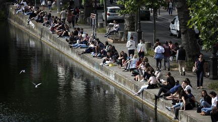 Des&nbsp;personnes assises le long du canal Saint-Martin à Paris, le 24 mai 2020 (photo d'illustration). (THOMAS COEX / AFP)