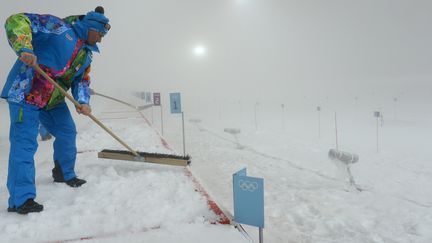 Un volontaire transporte de la neige autour des stands de tirs de l'&eacute;preuve de biathlon, le 16 f&eacute;vrier 2014 &agrave; Sotchi (Russie). (KIRILL KUDRYAVTSEV / AFP)