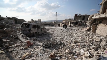 Des habitants du village d'Al-Bara (Syrie) au milieu de bâtiments détruits par des frappes aériennes, samedi 7 décembre 2019. (OMAR HAJ KADOUR / AFP)