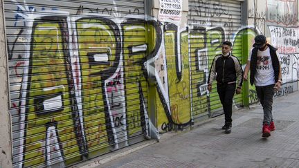 Des&nbsp;jeunes chiliens passent devant un graffiti en référence au référendum du 25 octobre visant à modifier la constitution du pays, à Santiago le 21 octobre 2020. Photo d'illustration. (MARTIN BERNETTI / AFP)