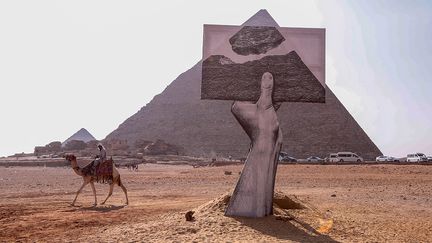 Pour créer un pont entre réel et virtuel, le street artiste JR a réalisé un trompe-l’œil où le spectateur placé à un certain endroit peut avoir l’impression de voir un morceau de la&nbsp; pyramide de Guizeh en lévitation. Cette œuvre a nécessité l’assemblage de 4591 photos correspondant à l’âge du monument.&nbsp; (ZIAD AHMED / NURPHOTO / AFP)