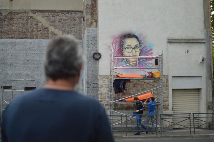 Un passant devant la fresque dévoilée d'Aïcha Issadounène par C215 à Saint-Ouen. (VICTOR VASSEUR / FRANCE-INFO)