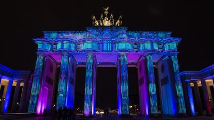 La façade de la porte de l'emblématique porte de Brandebourg est illuminé. (JOHN MACDOUGALL / AFP)