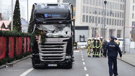 Un policier et des pompiers le 20 décembre 2016, près du camion qui a foncé sur la foule la veille, à Berlin (Allemagne). (TOBIAS SCHWARZ / AFP)