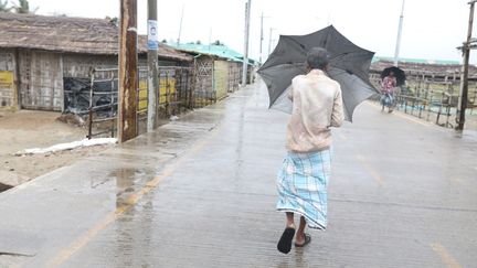 Un habitant de Cox's Bazar (Bangladesh) marche dans l'eau après le passage du cyclone Mocha, le 14 mai 2023. (ZAKIR HOSSAIN CHOWDHURY / ANADOLU AGENCY / AFP)