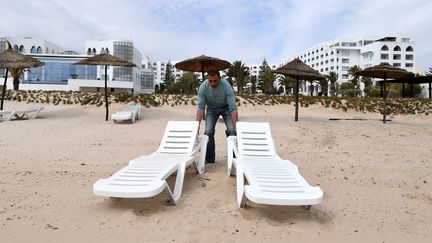 Un employé de l'Imperial Merhaba Hotel&nbsp;de Port El-Kantaoui dispose des chaises longues sur la plage, le 21 avril 2017, à Sousse (Tunisie). (FETHI BELAID / AFP)