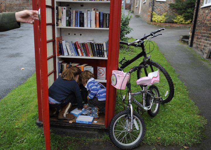 Un habitant du village de Marton cum Grafton, dans le Yorkshire du Nord (Grande-Bretagne), profite avec ses enfants d'une cabine t&eacute;l&eacute;phonique transform&eacute;e en biblioth&egrave;que, le 9 octobre&nbsp;2010. (NIGEL RODDIS/REUTERS)