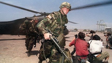 photographient l’arrivée des soldats américains à Port-au-Prince à Haïti, le 19 septembre 1994, dans le cadre de l'opération « Rétablir la démocratie », mise en place par Bill Clinton. 

Cette opération visait à rétablir au pouvoir Jean-Bertrand Aristide, élu en 1990, mais contraint de s’exiler aux États-Unis pendant trois ans à la suite d’un coup d’Etat en septembre 1991. (AFP / JAIME RAZURI)