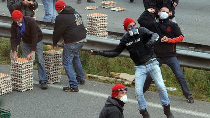 Des manifestants anti-&eacute;cotaxe jettent des &oelig;ufs sur les CRS, le 26 octobre 2013, &agrave; Pont-de-Buis (Finist&egrave;re). (FRED TANNEAU / AFP)