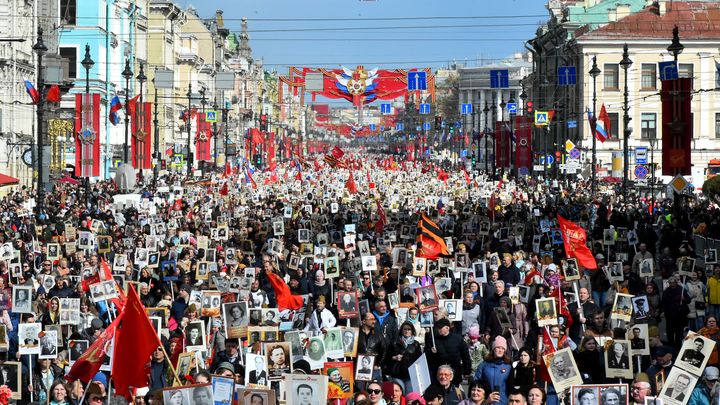 Des personnes portent des portraits de leurs proches - des soldats de la Seconde Guerre mondiale - alors qu'ils participent à la marche du Régiment immortel dans le centre de Saint-Pétersbourg, le 9 mai 2022. (OLGA MALTSEVA / AFP)