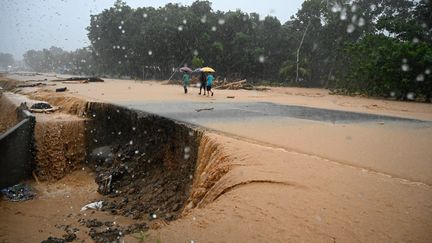 Des personnes marchent sur une route endommagée par les pluies diluviennes de l'ouragan Eta, le 4 novembre 2020, à Toyos (Honduras). (ORLANDO SIERRA / AFP)