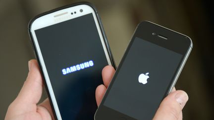 Une femme tient un iPhone, du constructeur Apple, dans une main et un Galaxy, du constructeur Samsung, dans l'autre, le 30 mars 2014, à Hambourg (Allemagne). (MARCUS BRANDT / DPA / AFP)