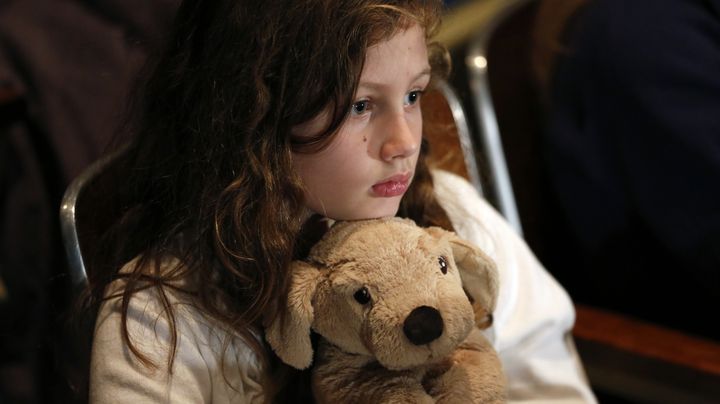 Une petite fille se recueille en la m&eacute;moire des 26 personnes tu&eacute;es par Adam Lanza, &agrave; Newtown (Connecticut, Etats-Unis), le 16 d&eacute;cembre 2012. (KEVIN LAMARQUE / REUTERS)