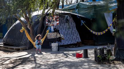 Une fille salvadorienne est assise près d'une affiche de la campagne Biden-Harris à l'intérieur d'un camp pour demandeurs d'asile le 7 février 2021 à Matamoros, au Mexique, créé dans le cadre de la politique de Donald Trump "Rester au Mexique". (JOHN MOORE / GETTY IMAGES NORTH AMERICA / AFP)