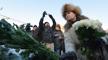 Une femme d&eacute;pose des fleurs sur un monument d&eacute;di&eacute; aux victimes de la r&eacute;pression politique, pendant une manifestation anti-Poutine, &agrave; Moscou, samedi 15 d&eacute;cembre 2012.&nbsp; (NATALIA KOLESNIKOVA / AFP)