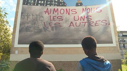 Kevin et Warrick, deux participants au projet, devant une des photos emblématiques réalisées par les jeunes du quartier. (France 3 Normandie)