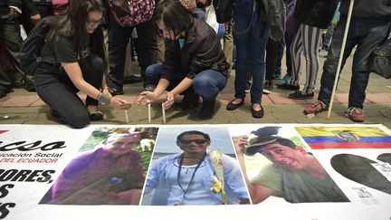 Des proches des journalistes Javier Ortega, Paul Rivas et de leur chauffeur Efrain Segarra allument des bougies, près de leurs photos, à Quito (Equateur), le 13 avril 2018.&nbsp; (RODRIGO BUENDIA / AFP)