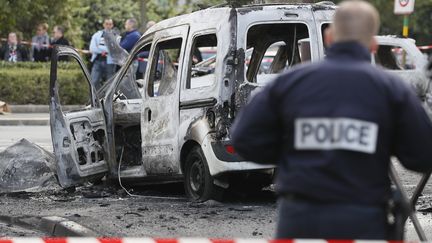 Un officier de police monte la garde près d'un véhicule de police incendié à Viry-Châtillon (Essonne) le 8 octobre 2016.&nbsp; (THOMAS SAMSON / AFP)