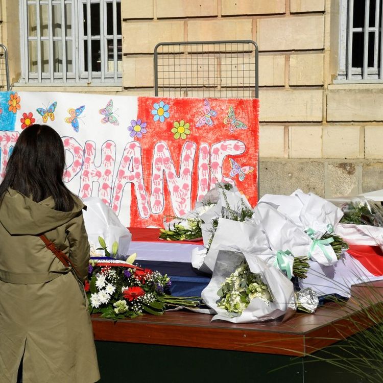 Une femme se recueille, le 26 avril 2021, devant un message et des fleurs en hommage à&nbsp;Stéphanie Monfermé, la fonctionnaire de police tuée lors d'une attaque au couteau au commissariat de Rambouillet (Yvelines). (BERTRAND GUAY / AFP)