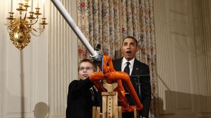 Le pr&eacute;sident am&eacute;ricain Barack Obama (D) assiste &agrave; une d&eacute;monstration de lancer de marshmallow gr&acirc;ce &agrave; un canon pr&eacute;sent&eacute; par son jeune inventeur (G) dans le cadre de la White House Science Fair &agrave; Washington, le 7 f&eacute;vrier 2012. (KEVIN LAMARQUE / REUTERS)