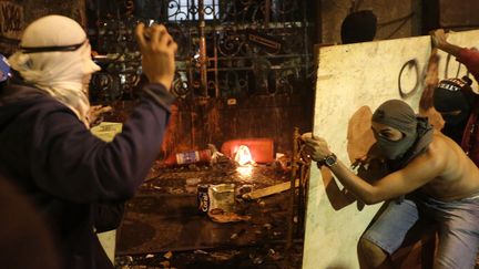 Des "Black blocs", des anarchistes masqu&eacute;s, s'attaquent &agrave; la porte de la mairie de Rio (Br&eacute;sil) apr&egrave;s une manifestation de soutien aux enseignants en gr&egrave;ve, le 7 octobre 2013. (RICARDO MORAES / REUTERS)