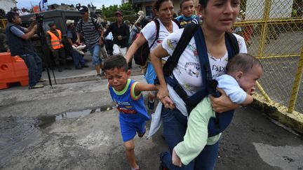 Les réfugiés honduriens se précipitent sur le pont reliant le Guatemala au Mexique, après avoir réussi à faire céder la barrière qui les retenait, le 19 octobre 2018. (PEDRO PARDO / AFP)