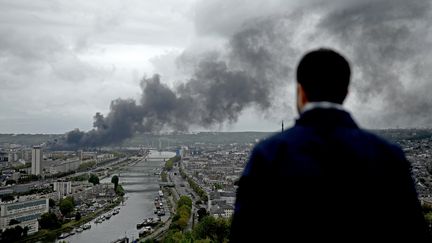 Un homme regarde le panache de fumée s'élever au dessus de Rouen (Seine-Maritime), le 26 septembre 2019. (PHILIPPE LOPEZ / AFP)