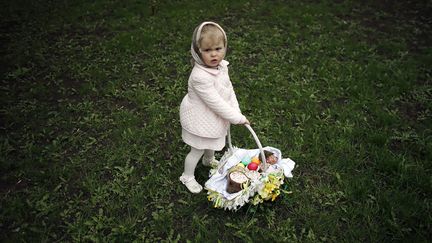 Une petite fille porte un panier rempli d'oeufs dans un parc &agrave; Donetsk (Ukraine), le 20 avril 2014. ( MARKO DJURICA / REUTERS)