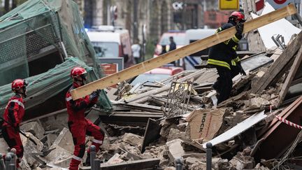 Des pompiers inspectent le batiment effondré. (SAMEER AL-DOUMY / AFP)