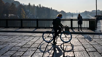 Une femme traverse à vélo le pont Vittorio Emanuele I dans le centre-ville de Turin, pendant la pandémie de Covid-19, le 17 novembre 2020. (MIGUEL MEDINA / AFP)