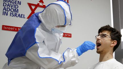 Un agent des services paramédicaux israéliens réalise un test de contamination au coronavirus au centre national des opérations, à Kiryat Ono, près de Tel-Aviv. (JACK GUEZ / AFP)