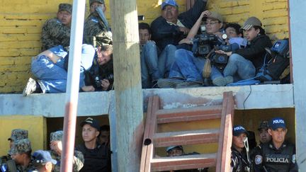 Des journalistes se prot&egrave;gent lors d'affrontements entre les familles des victimes de l'incendie et des policiers &agrave; la prison de Comayagua (Honduras), le 15 f&eacute;vrier 2012. (GUSTAVO AMADOR / EPA / MAXPPP)