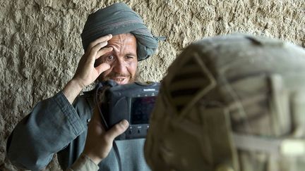 Un villageois &eacute;carte ses paupi&egrave;res lors d'une s&eacute;ance photo d'identification men&eacute;e par un soldat am&eacute;ricain, &agrave; Nevay Deh (Afghanistan), le 5 septembre 2012. (TONY KARUMBA / AFP)