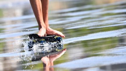 Un homme roule en skateboard près d'une fontaine à Nantes (Loire-Atlantique), lundi 19 juin 2017. Le département est placé en vigilance orange à la canicule par Météo-France. (LOIC VENANCE / AFP)