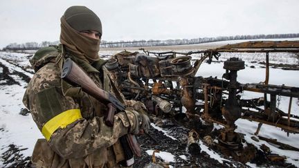 Un soldat de la 93e Brigade motorisée de l'armée ukrainienne inspecte un véhicule militaire détruit, à un endroit non précisé par l'armée ukrainienne, qui a diffusé ce cliché le 8 mars 2022. (STR / AFP)