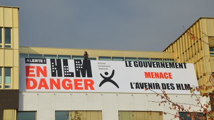 Une affiche lors d'une manifestation contre la baisse des APL couplée à une baisse des loyers dans les logements sociaux, le 15 novembre 2017 à Saint-Denis (Seine-Saint-Denis).&nbsp; (ALPHACIT NEWIM / CITIZENSIDE / AFP)