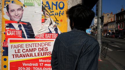 Un homme passe devant une affiche de campagne de Benoît Hamon, à Toulouse (Haute-Garonne) le 15 mars 2017. (ERIC CABANIS / AFP)