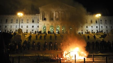 Des pancartes br&ucirc;lent devant le Parlement portugais, gard&eacute; par la police anti&eacute;meute, apr&egrave;s une manifestation contre l'aust&eacute;rit&eacute; &agrave; Lisbonne, le 15 octobre 2012. (PATRICIA DE MELO MOREIRA / AFP)