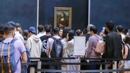 Des visiteurs du musée du Louvre devant La Joconde, le célèbre portrait de Mona Lisa peint par Léonard de Vinci, en mai 2022. (VINCENT ISORE / MAXPPP)