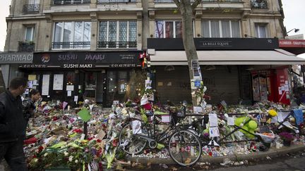 Des passants s'arrêtent devant le café "La Belle Equipe", frappé par les attentats, le 18 novembre 2015.&nbsp; (BERTRAND GUAY / AFP)