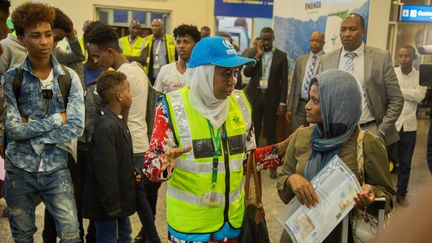 La responsable rwandaise de la protection des réfugiés, Zahra Mirghani (C), accueille la première arrivée de 66 réfugiés et demandeurs d'asile en provenance de Libye à l'aéroport international de Kigali, le 26 septembre 2019. (CYRIL NDEGEYA / RWANDA'S MINISTRY OF EMERGENCY M)