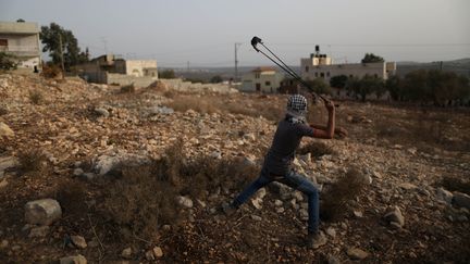 Un jeune Palestinien lance une pierre sur des soldats isra&eacute;liens &agrave; Qadomem, en Cisjordanie, le 12 septembre 2015. (AHMAD TALAT / NURPHOTO / AFP)