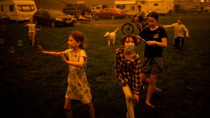 Des enfants jouent près de la ville de Bega en Australie, où le feu fait rage, le 31 décembre 2019. (SEAN DAVEY / AFP)