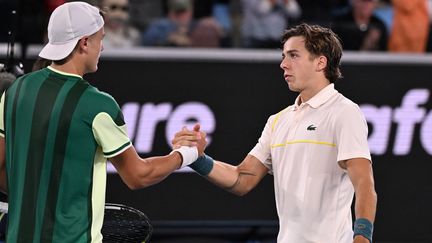 Poignée de main entre deux joueurs qui se connaissent bien pour s'être affrontés chez les juniors : Holger Rune et Arthur Cazaux, après la victoire du Français au 2e tour de l'Open d'Australie, le 18 janvier 2024. (WILLIAM WEST / AFP)