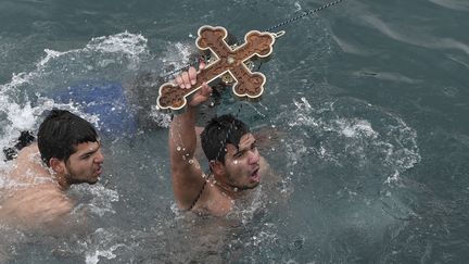 Celui&nbsp;qui&nbsp;repêche&nbsp;la croix jetée en mer est&nbsp;béni par le pope lors de l'Epiphanie orthodoxe. Ici, l'heureux élu du 6 janvier 2020 dans le village de Pachi, près d'Athènes.&nbsp; (LOUISA GOULIAMAKI / AFP)