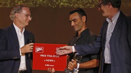 Le photographe grec Aris Messinis (AFP) reçoit le Visa d'or "News" à Perpignan des mains d'Olivier Royan (à gauche) et de Jean-François Leroy (à droite)
 (Raymond Roig / AFP)