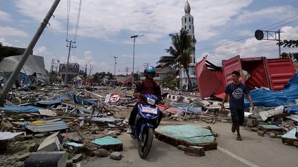 Des habitants de l'île des Célèbes se frayent un chemin parmi les décombres, le 29 septembre 2018. La veille, un séisme et un tsunami ont frappé cette région indonésienne. (MUHAMMAD RIFKI / AFP)