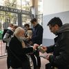 Françoise, soutien de Yannick Jadot, distribue des tracts aux militants lors d'un porte-à-porte, dans le 14e arrondissement de Paris, le 30 mars 2022. (MARGAUX DUGUET / FRANCEINFO)