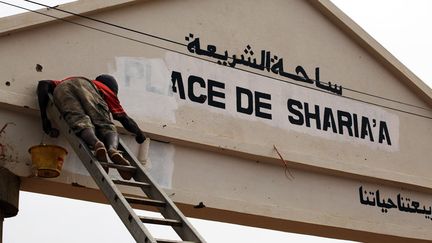 Un employ&eacute; municipal d&eacute;baptise la place Charia apr&egrave;s 9 mois d'occupation des islamistes &agrave; Gao (Mali), le 3 mars 2013. (REUTERS)